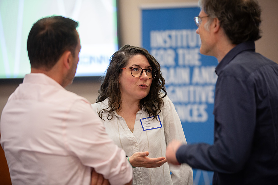 Three Institute-affiliated faculty members have a conversation in front of an IBACS banner.