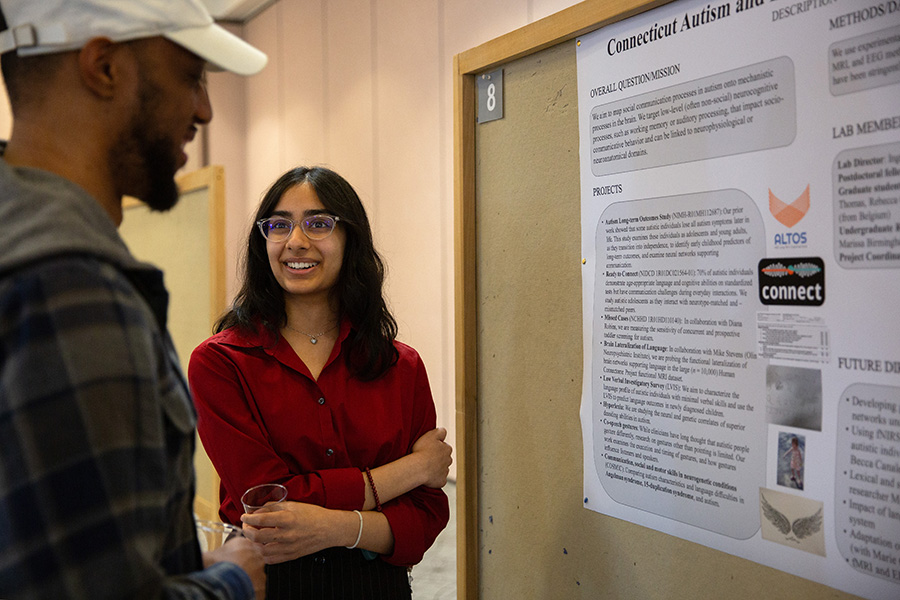 Two students discuss a research poster.