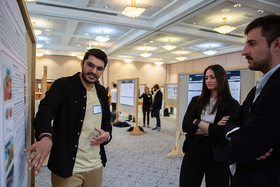 A research presents their work at a poster presentation event.