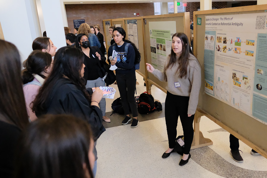 A student presents research to a crowd during a Language Fest poster session.